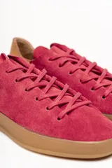 Zapatilla de cuero vacuno color rojo, con cordones al tono y suela de caucho color caramelo. Detalle de cuero vacuno color tostado en el talón.