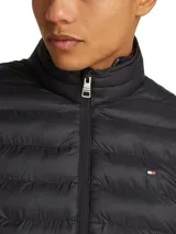 Campera puffer negra Tommy Hilfiger, con cuello alto, cierre frontal con cremallera, bolsillos laterales y logo bordado en el pecho.