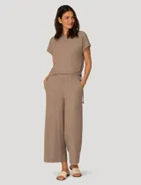 Conjunto de dos piezas compuesto por una remera de manga corta con cuello redondo y frunces laterales ajustables, y un pantalón de corte ancho con cintura elástica y bolsillos laterales.