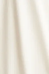 Pantalón de pijama color crema en punto pointelle, con piernas levemente acampanadas. Tiene cintura elástica revestida, ribete de volados y cordón fino para ajustar.