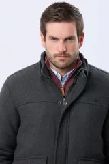 Saco de paño color gris oscuro, con capucha desmontable, cierre frontal oculto por cartera con botones a presión y bolsillos laterales. Presenta un diseño de abrigo estructurado con forro interior.