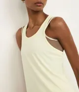 Musculosa deportiva de corte nadador, color amarillo claro, confeccionada en microfibra con textura perforada. Presenta escote en U y diseño holgado con pliegue en la espalda.