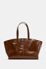 Bolso tipo shopper de cuero en color marrón, con diseño de doble asa de hombro, costuras decorativas y cierre mediante botón imantado.