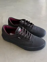 Championes de skate Vans modelo Curren Caples, color negro con detalles en bordó en el interior. Presentan una parte superior de cuero y ante con refuerzos Duracap, suela de goma SickStick y plantilla PopCush.