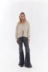 Cardigan de tejido de punto color marrón, con cuello solapa, cierre frontal de cremallera y diseño de trenzas. Cuenta con puños y dobladillo en rib elástico y un pequeño bordado en el pecho.