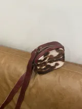 Bandolera de cuero marrón con panel frontal de piel sintética con estampado animal en tonos verde oliva y marrón. Tiene correa larga regulable, cierre superior con cremallera y forro interior.