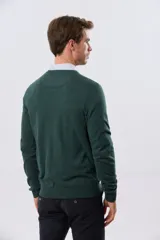 Buzo tejido de algodón color gris melange, de diseño clásico con escote en V, mangas largas y puños y ruedo acanalados. Cuenta con un pequeño bordado en el pecho.