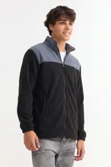 Campera de polar con cierre frontal completo, cuello alto y diseño bicolor en gris y negro. Cuenta con bolsillos laterales y puños elásticos.