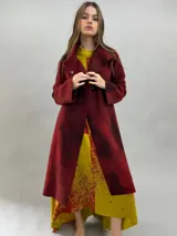 Tapado de lana merino afieltrada con diseño artesanal teñido en tonos violeta y fucsia. Presenta cuello elevado, cierre frontal con broches ocultos, bolsillos laterales y un corte ligeramente más largo en la parte trasera.