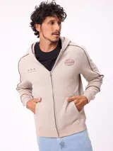 Canguro gris con capucha, cierre frontal completo y bolsillos tipo canguro. Presenta detalles de líneas blancas en las mangas y estampados gráficos en el pecho.