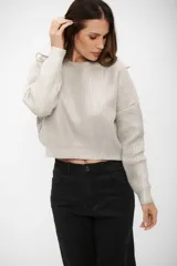 Buzo de tejido de punto con acabado brillante, cuello redondo, mangas largas y corte cropped.