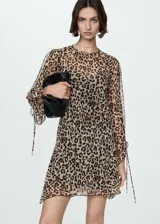 Vestido corto de tejido fluido y semitransparente con estampado animal print de leopardo. Presenta cuello redondo, diseño recto y mangas largas con detalle de lazo ajustable en los puños. Incluye forro interior.