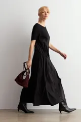 Vestido largo negro oversized con cuello redondo, mangas cortas y detalle fruncido en la cintura con cordón ajustable.