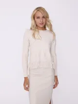 Sweater color beige de tejido de punto trenzado con cuello redondo y mangas largas. Presenta detalle de flecos en el ruedo.