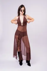 Vestido largo de tul color marrón con diseño de top halter y falda con volados laterales. Presenta una estructura de malla semitransparente que aporta movimiento y elegancia.
