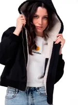 Chaqueta de lona color negro con forro interior de sherpa, cierre frontal con cremallera, capucha y puños elásticos.