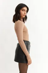 Polera de tejido de punto color beige con brillo metalizado, cuello alto y mangas largas.