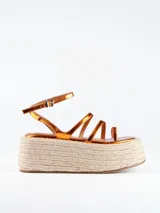 Sandalia con plataforma de esparto, tiras color cobre y cierre con hebilla al tobillo.