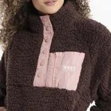 Campera de polar tipo sherpa color verde, con cuello alto y cierre frontal parcial con botones a presión. Presenta un bolsillo frontal con cierre y detalle de marca Reef.