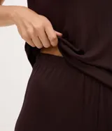 Pijama corto Lov de color marrón oscuro, confeccionado en viscolycra. Consta de una blusa de manga corta con escote en V decorado con encaje y un short con cintura elástica.