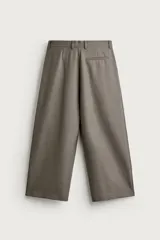Pantalón relaxed fit de color blanco off-white, confeccionado en tejido con lino. Cuenta con pliegues frontales en la cintura, bolsillos delanteros y cierre frontal con cremallera y botón.