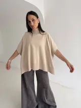 Poncho de tejido de punto color marrón chocolate, con cuello alto tipo polera y mangas cortas amplias. Presenta un diseño holgado con terminaciones acanaladas en el ruedo.