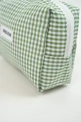 Neceser de tela con estampado de cuadros vichy en color verde y blanco. Cuenta con una etiqueta frontal con el logo de la marca y un tirador de cierre en color rosado.