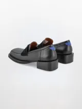 Mocasín plateado de cuero con punta cuadrada, detalle de estrella y talón en rojo.