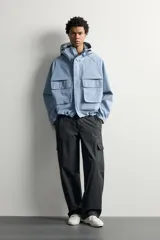 Cazadora cropped fit de tejido técnico negro repelente al agua, con cuello subido, capucha ajustable, bolsillos frontales de plastrón con solapa, mangas largas con puños elásticos y bajo ajustable con cordón.