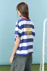 Remera de algodón con diseño de rayas horizontales azules y blancas, cuello redondo en color rojo con detalle de costura en zigzag y bordado frontal con la palabra Yorugua.