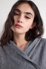 Jersey estilo sudadera gris con capucha, escote en pico y diseño cruzado en la parte frontal.