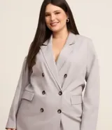 Blazer de corte sastrero color gris claro, con solapas, abotonado doble, forro interno y bolsillos frontales decorativos con solapa.