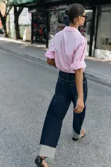 Jeans de tiro medio color azul oscuro, con cinco bolsillos, cierre de cremallera y botón. Presenta una silueta curvada, más ancha en el muslo y la rodilla, y un bajo con vuelta.