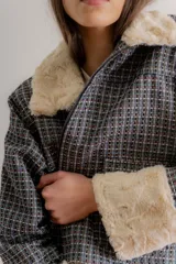 Chaqueta de jacquard con diseño a cuadros, cuello y puños de piel sintética, cierre frontal y bolsillos laterales.