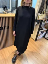 Vestido midi color beige de tejido acanalado, con cuello alto y mangas largas.