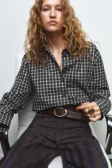 Camisa oversize de algodón con estampado de cuadros, cuello solapa, manga larga con puños y cierre frontal con botones. Presenta un detalle de pañuelo integrado en el mismo tejido que se anuda en la parte frontal.