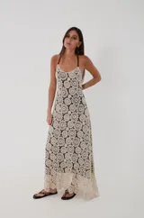 Vestido largo de crochet color crudo con motivo de medallones y forro interior negro. Cuenta con escote en V, espalda descubierta y tirantes de cuero marrón.