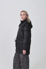 Campera puffer negra de corte largo y holgado, con capucha, cierre frontal y bolsillos delanteros con solapa.