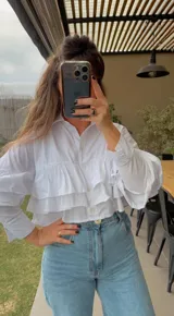 Camisa fucsia de popelina con volados en el frente y mangas largas.