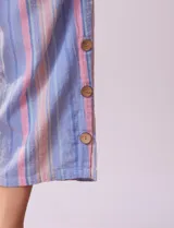 Pantalón de algodón estampado a rayas verticales azules y blancas, marca Erika. Tiene pretina elastizada, bolsillos delanteros, ruedo lateral con tajo y botones decorativos.