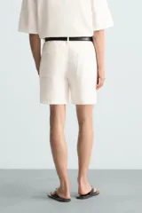 Bermuda de algodón color blanco, de corte relajado, con cintura elástica, bolsillos frontales y bolsillos traseros de plastrón. Cierre frontal con cremallera y botón.