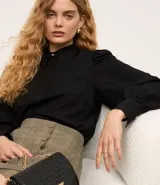 Camisa celeste de crepé con cuello inglés, manga larga abullonada y abotonadura frontal.