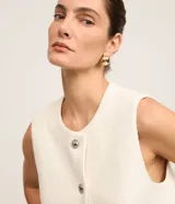 Chaleco blanco de tweed con cuello redondo, abotonado en el frente y corte entallado.