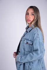 Campera oversize de denim de algodón en color celeste, con diseño de hombros caídos, bolsillos con solapa en el pecho y cierre frontal con botones.