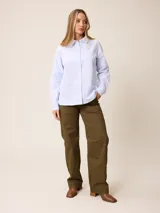 Camisa de manga larga con cuello clásico y cierre frontal de botones, confeccionada en tela de algodón con diseño de rayas verticales finas en color rosado y blanco. Presenta un bolsillo frontal en el pecho con detalle de etiqueta pequeña.