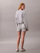 Buzo cropped de cuello redondo, confeccionado en algodón regenerativo, con puños y dobladillo en punto canalé y detalle de insignia con logotipo de la marca.