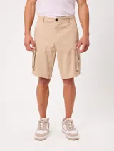 Bermuda cargo de gabardina color beige, con bolsillos laterales con fuelle en las piernas, bolsillos delanteros tipo ojal y traseros. Cuenta con presillas para cinto y cierre frontal con botón y cierre.