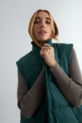 Chaleco acolchado color chocolate con interior y cuello de corderito sintético. Presenta cierre frontal con botones a presión y bolsillos laterales.