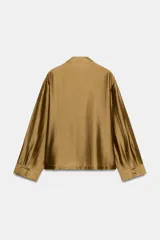 Camisa de estilo oriental confeccionada en mezcla de lyocell con acabado satinado. Presenta cuello redondo, manga larga con puños rectos, bolsillos de plastrón y cierre frontal mediante alamares.