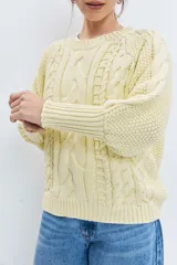 Sweater de punto en color celeste, con diseño de trenzas y textura en relieve. Presenta cuello redondo, mangas largas con puños ajustados y un corte holgado.